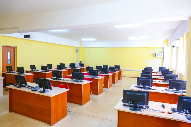 Rows of desktop computers on wooden desks in a bright university computer laboratory